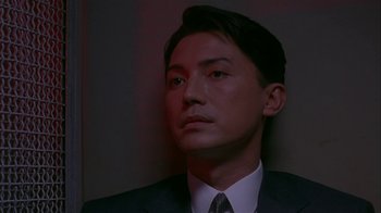 Movie still from “M. Butterfly” (1993), directed by David Cronenberg – A person wearing a suit and tie; Close Up shot, Low angle