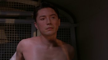 Movie still from “M. Butterfly” (1993), directed by David Cronenberg – A man with no shirt is looking at the camera; Close Up shot, Low angle