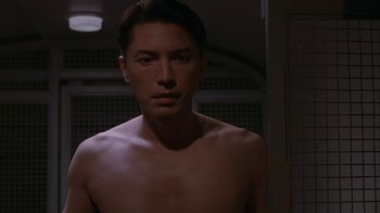 Movie still from “M. Butterfly” (1993), directed by David Cronenberg – A man with no shirt is looking at the camera; Close Up shot, Low angle