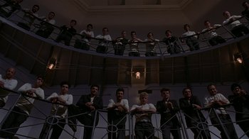 Movie still from “M. Butterfly” (1993), directed by David Cronenberg – A group of men standing on top of a metal railing next to each other; Wide shot, Low angle