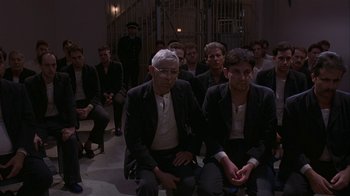 Movie still from “M. Butterfly” (1993), directed by David Cronenberg – A group of people sitting in a room; Wide shot, High angle