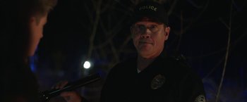 Movie still from “Ma” (2019), directed by Tate Taylor – A man in a police uniform holding a gun; Close Up shot, Over the shoulder angle