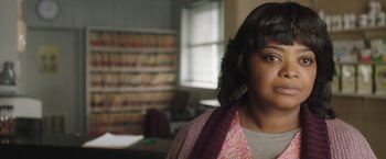 Movie still from “Ma” (2019), directed by Tate Taylor – A woman standing in front of a bookshelf in a room; Close Up shot, Over the shoulder angle