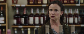 Movie still from “Ma” (2019), directed by Tate Taylor – A woman in a brown jacket is in front of a shelf of liquor bottles; Close Up shot, Over the shoulder angle