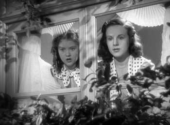 Movie still from “Mad About Music” (1938), directed by Norman Taurog – A young girl looking in a mirror at her reflection; Medium shot, Low angle