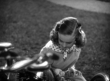 Movie still from “Mad About Music” (1938), directed by Norman Taurog – A little girl sitting on the ground next to a motorcycle; Close Up shot, High angle