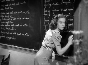 Movie still from “Mad About Music” (1938), directed by Norman Taurog – A woman writing on a blackboard with a marker; Medium shot, Over the shoulder angle