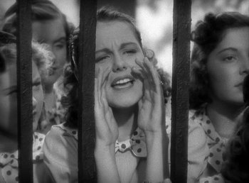 Movie still from “Mad About Music” (1938), directed by Norman Taurog – A group of young women standing next to each other in front of a fence; Close Up shot, Low angle