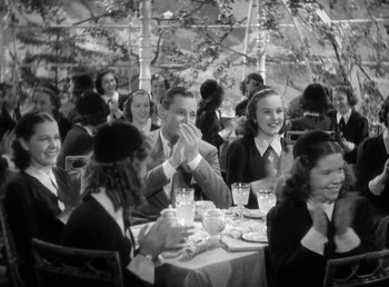 Movie still from “Mad About Music” (1938), directed by Norman Taurog – A black and white photo of people sitting at a table; Medium shot, High angle