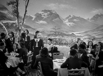 Movie still from “Mad About Music” (1938), directed by Norman Taurog – A group of people sitting at a table with mountains in the background; Wide shot, High angle