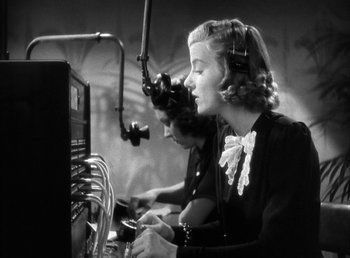 Movie still from “Mad About Music” (1938), directed by Norman Taurog – A woman in a black dress and a microphone; Close Up shot, Low angle