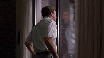 Movie still from “Mad Dog and Glory” (1993), directed by John McNaughton – A man standing in front of a window looking outside; Medium shot, Over the shoulder angle