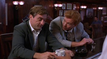 Movie still from “Mad Dog and Glory” (1993), directed by John McNaughton – Two men in business suits are sitting at a bar; Medium shot, Over the shoulder angle