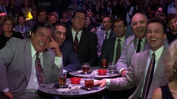 Movie still from “Mad Dog and Glory” (1993), directed by John McNaughton – A group of men sitting at a table with drinks in front of them; Medium shot, High angle