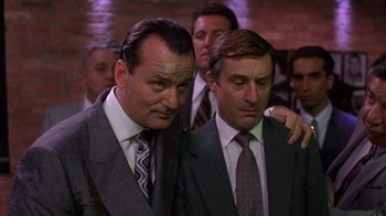 Movie still from “Mad Dog and Glory” (1993), directed by John McNaughton – A couple of men standing next to each other; Medium shot, Low angle