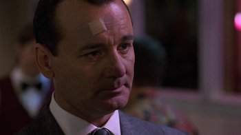 Movie still from “Mad Dog and Glory” (1993), directed by John McNaughton – A person wearing a suit with a bandage on his head; Close Up shot, Low angle