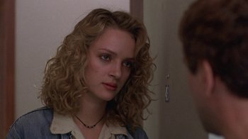 Movie still from “Mad Dog and Glory” (1993), directed by John McNaughton – A woman with long blonde curly hair looking at a mirror; Close Up shot, Over the shoulder angle