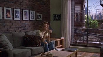 Movie still from “Mad Dog and Glory” (1993), directed by John McNaughton – A woman sitting on top of a couch holding a cell phone; Wide shot, Over the shoulder angle