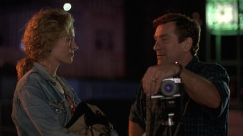 Movie still from “Mad Dog and Glory” (1993), directed by John McNaughton – A man and a woman talking to each other while holding a video camera; Close Up shot, Over the shoulder angle