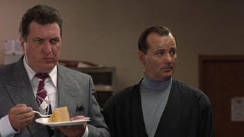 Movie still from “Mad Dog and Glory” (1993), directed by John McNaughton – Two men in suits are holding a plate of cake; Medium shot, Low angle