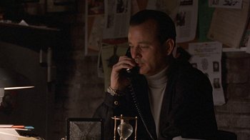 Movie still from “Mad Dog and Glory” (1993), directed by John McNaughton – A man talking on a phone while sitting at a desk; Medium shot, Low angle