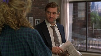 Movie still from “Mad Dog and Glory” (1993), directed by John McNaughton – A man in a suit and tie holding a newspaper; Close Up shot, Over the shoulder angle