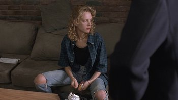 Movie still from “Mad Dog and Glory” (1993), directed by John McNaughton – A woman sitting on a couch eating a sandwich; Medium shot, Over the shoulder angle
