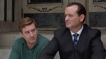 Movie still from “Mad Dog and Glory” (1993), directed by John McNaughton – Two men in business suits sitting next to each other; Close Up shot, Over the shoulder angle