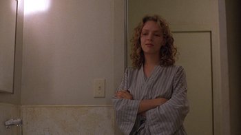 Movie still from “Mad Dog and Glory” (1993), directed by John McNaughton – A woman standing in front of a bathroom mirror with her arms crossed; Medium shot, Low angle