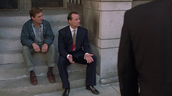 Movie still from “Mad Dog and Glory” (1993), directed by John McNaughton – A man in a suit sitting on steps next to another man in a suit; Medium shot, Low angle