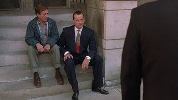 Movie still from “Mad Dog and Glory” (1993), directed by John McNaughton – A man in a suit and tie sitting on steps; Medium shot, Low angle