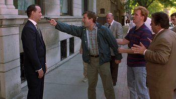 Movie still from “Mad Dog and Glory” (1993), directed by John McNaughton – A group of men standing on a sidewalk holding guns; Medium shot, Over the shoulder angle