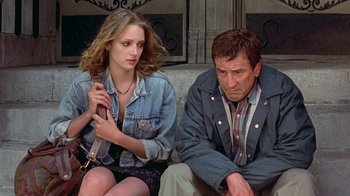 Movie still from “Mad Dog and Glory” (1993), directed by John McNaughton – A man and a woman sitting next to each other on the ground; Medium shot, Low angle