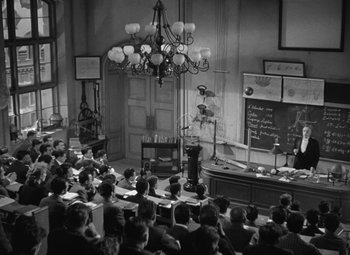 Movie still from “Madame Curie” (1943), directed by Mervyn LeRoy – An old photo of a class room full of students; Wide shot, High angle