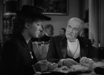 Movie still from “Madame Curie” (1943), directed by Mervyn LeRoy – An older man and a young woman sitting at a table; Medium shot, Over the shoulder angle