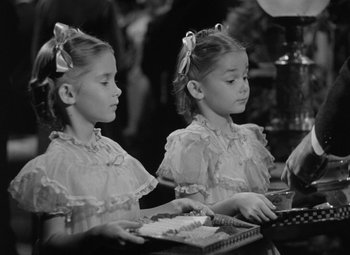 Movie still from “Madame Curie” (1943), directed by Mervyn LeRoy – Two little girls are sitting at a table; Medium shot, High angle