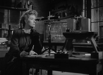 Movie still from “Madame Curie” (1943), directed by Mervyn LeRoy – A woman sitting at a desk in front of a computer monitor; Medium shot, Low angle