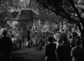 Movie still from “Madame Curie” (1943), directed by Mervyn LeRoy – A group of people gathered in a yard for an outdoor event; Wide shot, High angle