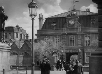 Movie still from “Madame Curie” (1943), directed by Mervyn LeRoy – A black and white photo of people walking in front of a building; Extreme Wide shot, High angle