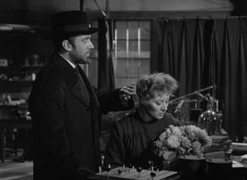 Movie still from “Madame Curie” (1943), directed by Mervyn LeRoy – A man and a woman are sitting at a table with flowers; Medium shot, Over the shoulder angle
