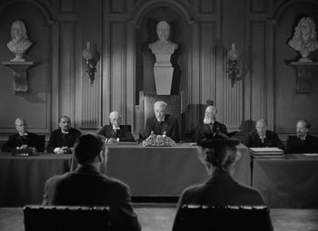 Movie still from “Madame Curie” (1943), directed by Mervyn LeRoy – A black and white photo of a court room; Wide shot, High angle