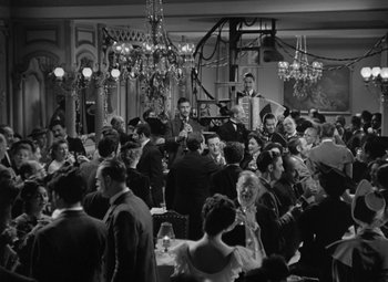 Movie still from “Madame Curie” (1943), directed by Mervyn LeRoy – A group of people sitting at a table in front of a chandelier; Extreme Wide shot, High angle