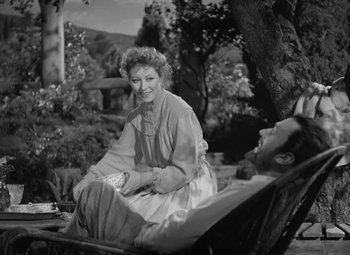 Movie still from “Madame Curie” (1943), directed by Mervyn LeRoy – An old photo of a woman sitting next to a man; Medium shot, High angle