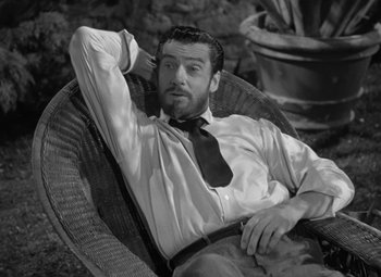 Movie still from “Madame Curie” (1943), directed by Mervyn LeRoy – A black and white photo of a man sitting in a chair; Medium shot, High angle