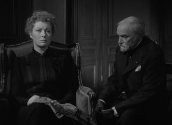 Movie still from “Madame Curie” (1943), directed by Mervyn LeRoy – An older man and a younger woman sitting next to each other; Medium shot, High angle