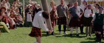 A man in a kilt holding a pole in front of a group of people in kilts