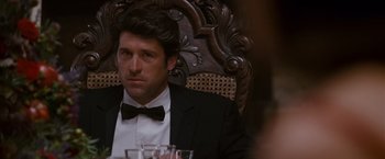 Movie still from “Made of Honor” (2008), directed by Paul Weiland – A person sitting in a chair wearing a suit; Close Up shot, Over the shoulder angle