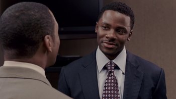 Movie still from “Madea Goes to Jail” (2009), directed by Tyler Perry – A man in a business suit talking to another man in a business suit; Close Up shot, Over the shoulder angle