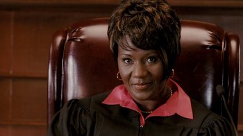 Movie still from “Madea Goes to Jail” (2009), directed by Tyler Perry – A woman sitting in a leather chair wearing a black robe; Close Up shot, High angle