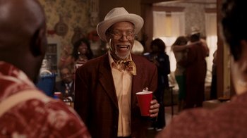 Movie still from “Madea Goes to Jail” (2009), directed by Tyler Perry – An older man wearing a hat and holding a drink; Medium shot, Over the shoulder angle
